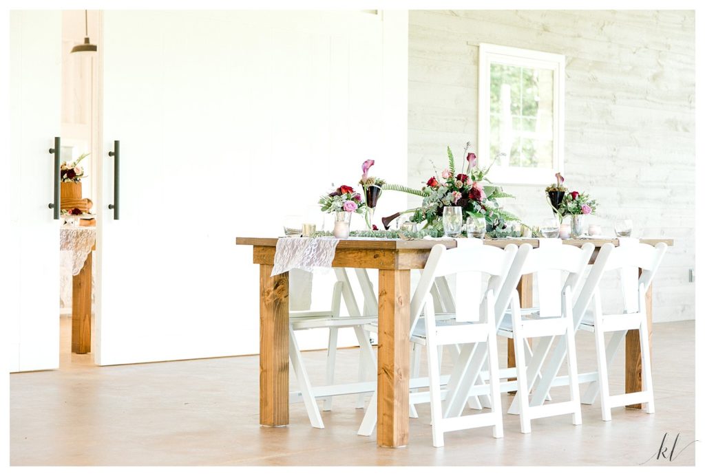 Set table with floral centerpieces on the outside porch of Mayfair Farm's Event Barn. 