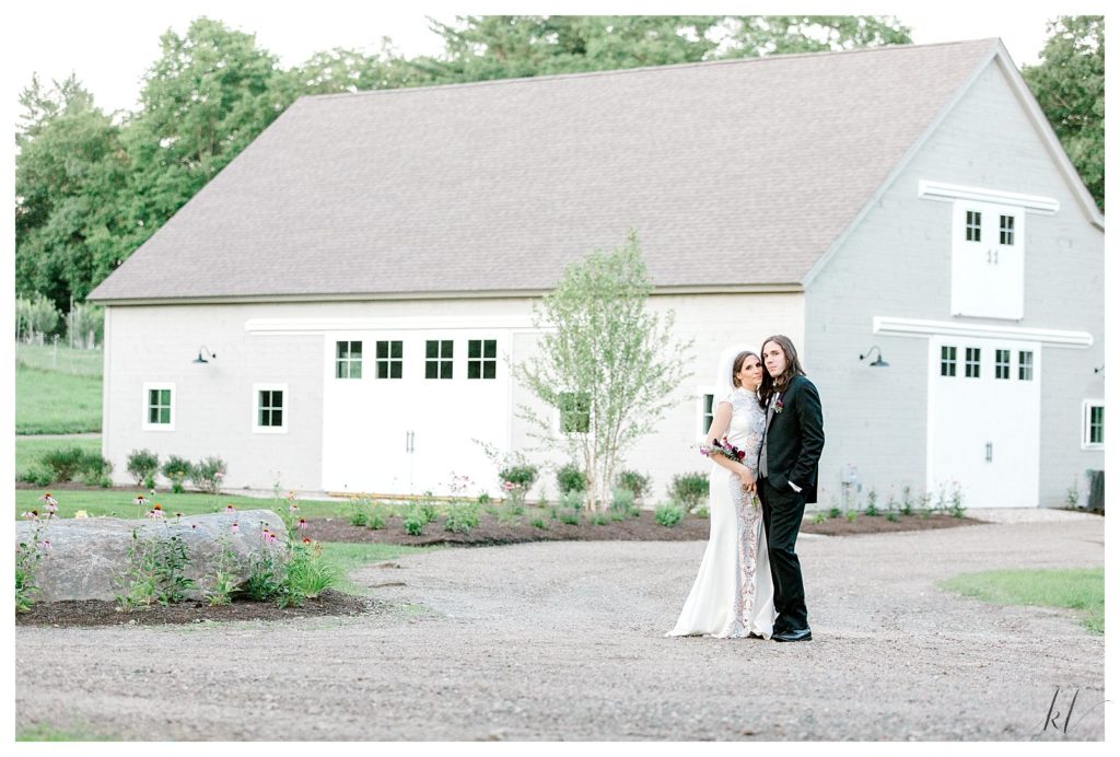 Bride and Groom pose for a portrait in front of the new White Wedding Barn at Mayfair Farms in NH. 