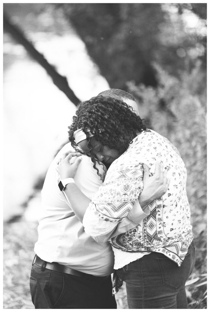 Black and White photo of a woman hugging her husband. 