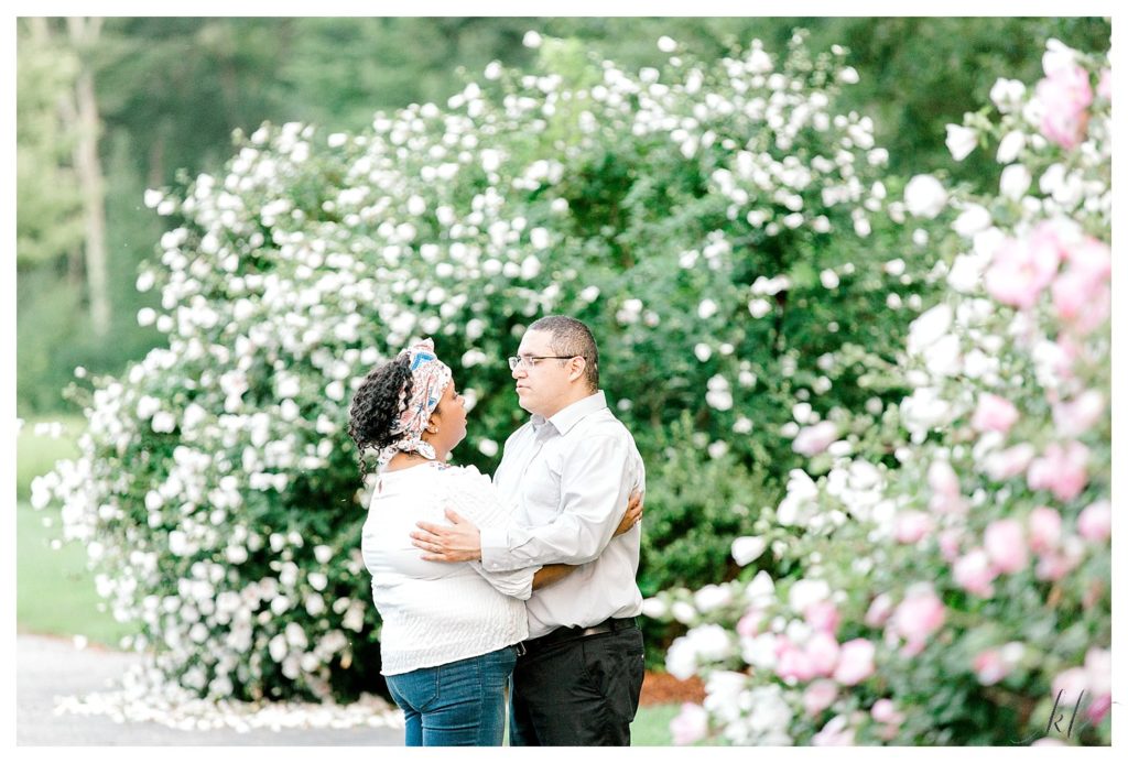 Candid photo of a man and woman talking in front of white flowering bushes at the Alpine Banquet Facility in Hollis NH. 