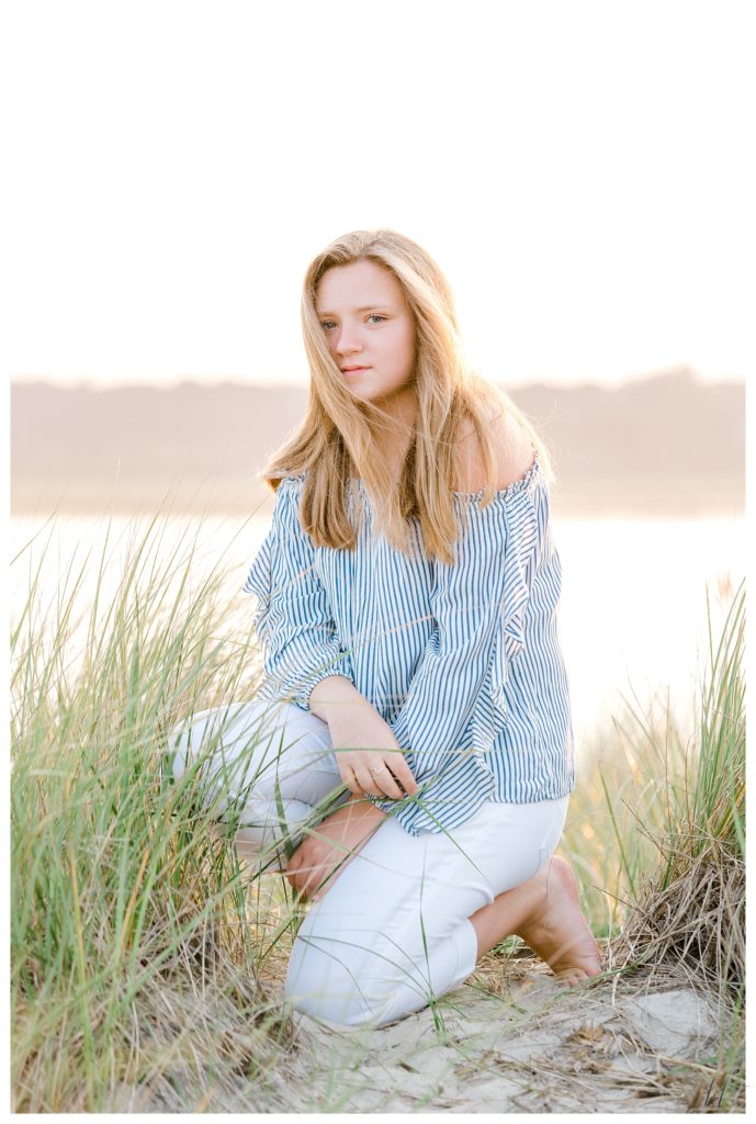 Senior portrait taken on Drakes Island in Wells maine of a girl wearing a striped blue and white shirt with White capris. 
