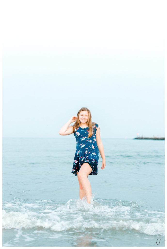 Fun and playful photo of a girl kicking the water on Drake's Island Beach during her senior photo session. 