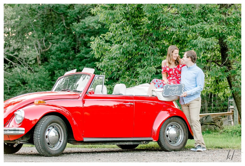 Engagement Photos with a Red 1972 VW Beetle with the girl sitting on the back holding a Save the Date sign. 
