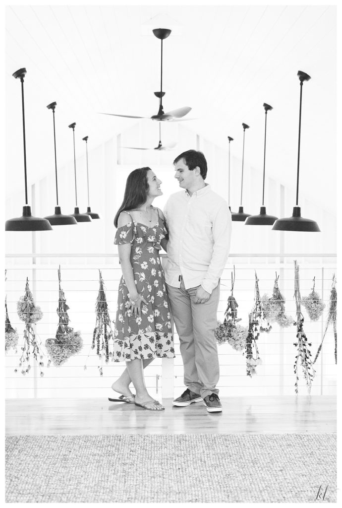 Black and White photo of an engaged couple posing for a portrait inside the renovated barn at Mayfair farm. 