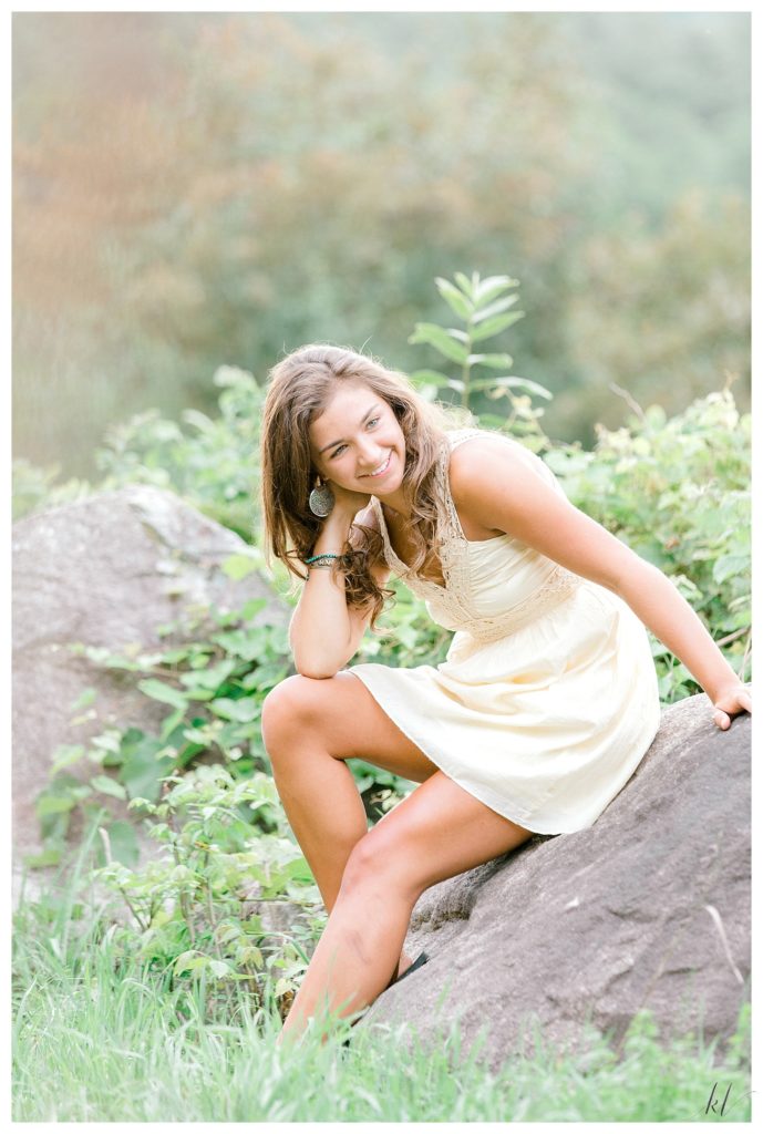 Light and Airy Senior Photos of a girl wearing a yellow dress while sitting on a Rock. K. Lenox Photography. 