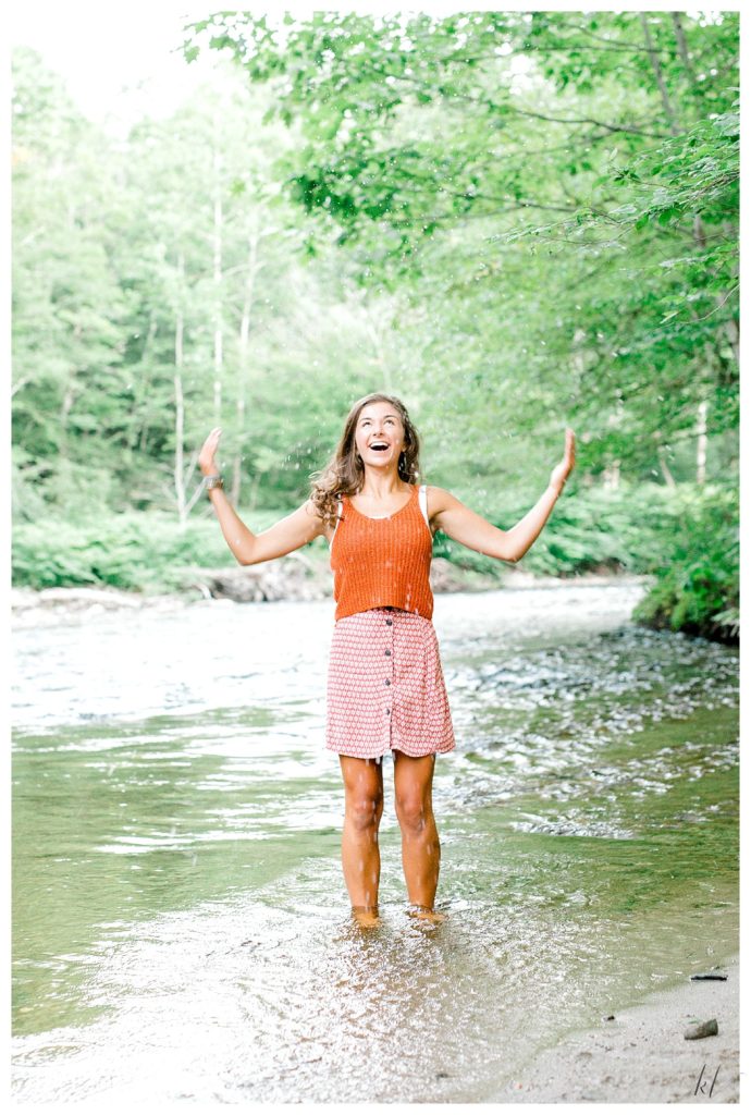 Light and Airy Candid photo of a girl playing in a river for her senior portrait session. 