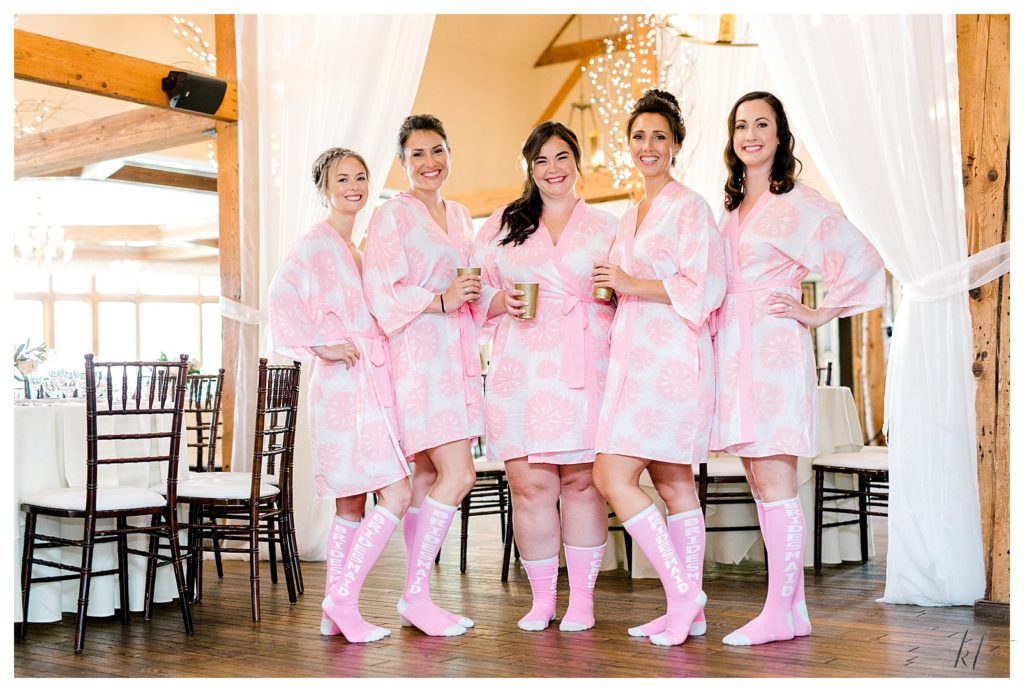 5 bridesmaids wearing pink floral robes show off their custom Bridesmaids pink knee high socks. 