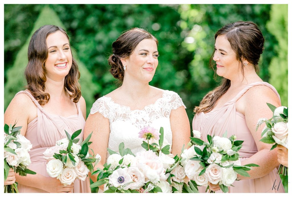 Bride wearing a Stella York dress is with her bridesmaids holding bouquets. 