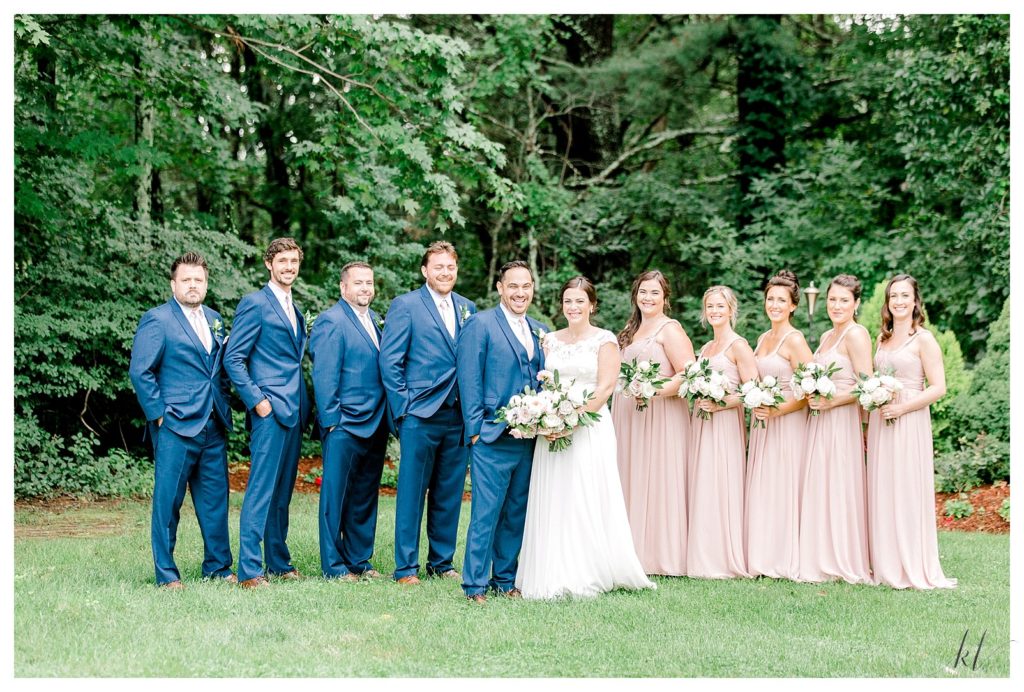 Traditional and classic wedding party photo. Groomsmen wearing Blue Tuxe's Bridesmaids wearing dusty pink dresses. 