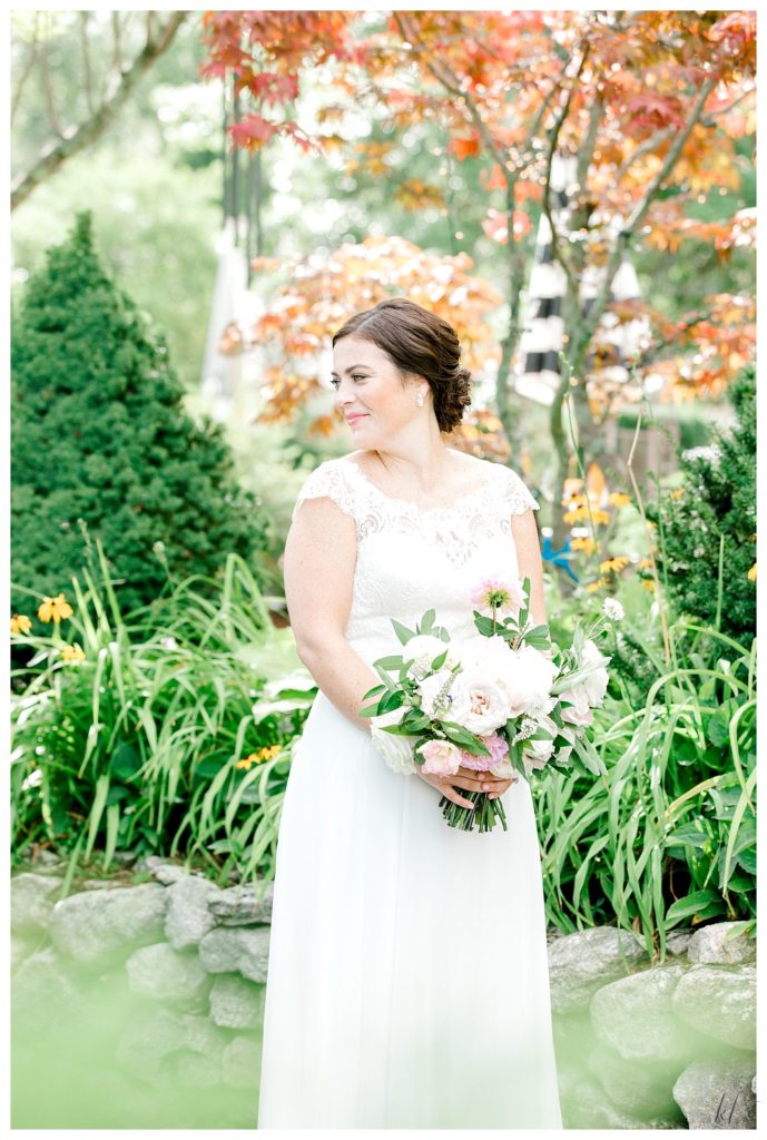 Candid photo of a bride wearing a Stella York dress- looking over her shoulder and holding a floral bouquet