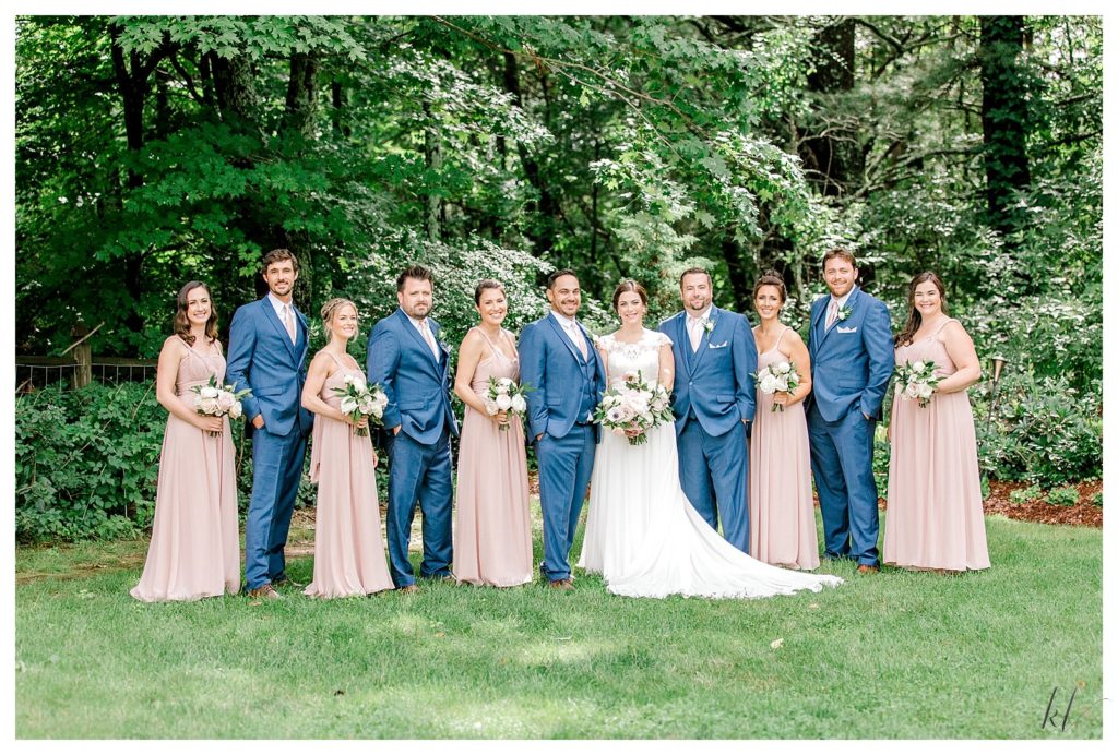 Wedding Party of 11 people including the bride and groom. Men wearing blue tux's, bridesmaids wearing dusty pink dresses. 