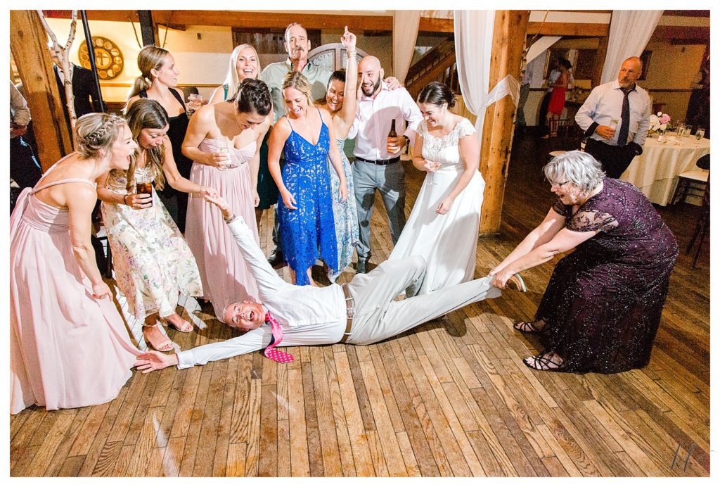 Guests of a wedding getting silly as they play for a picture on the dancefloor. 
