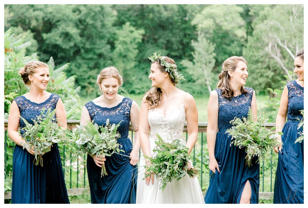 Candid photo of a bride walking with her Bridesmaids wearing blue dresses and holding green bridal bouquets. 