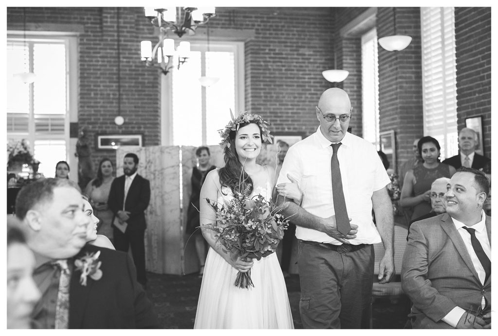 Black and White photo of a dad walking his daughter down the aisle in the Woven Label Board room at the Claremont Common Man Wedding