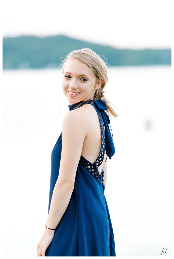 High School Senior girl wearing a blue dress poses near Spofford Lake in NH for a natural looking portrait. 