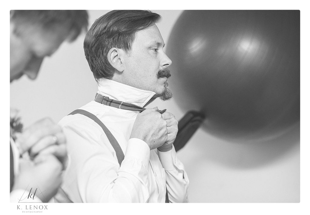 Black and White photo of a groom putting on his bowtie