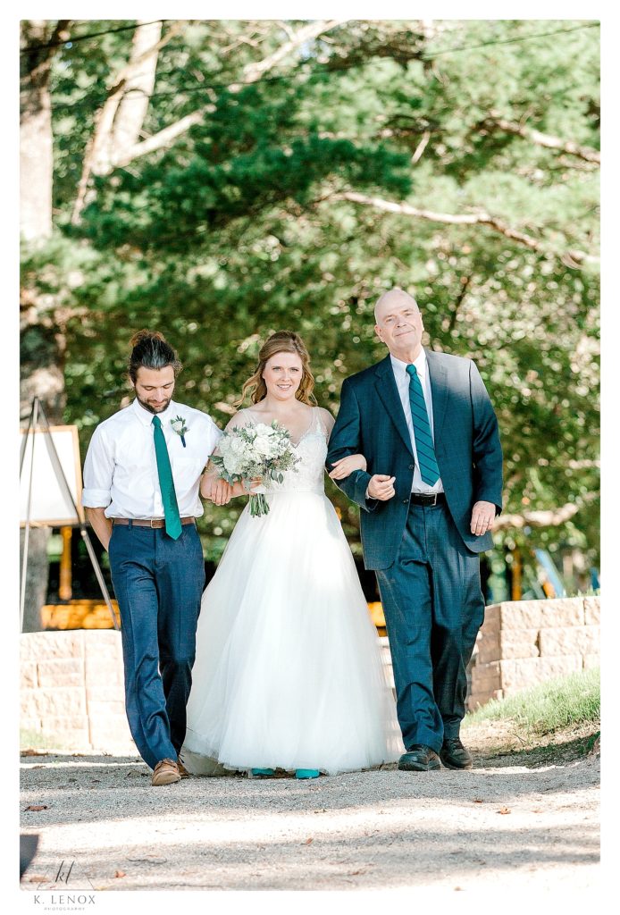 Bride is walked down the aisle of her camp wedding by her brother and father. 