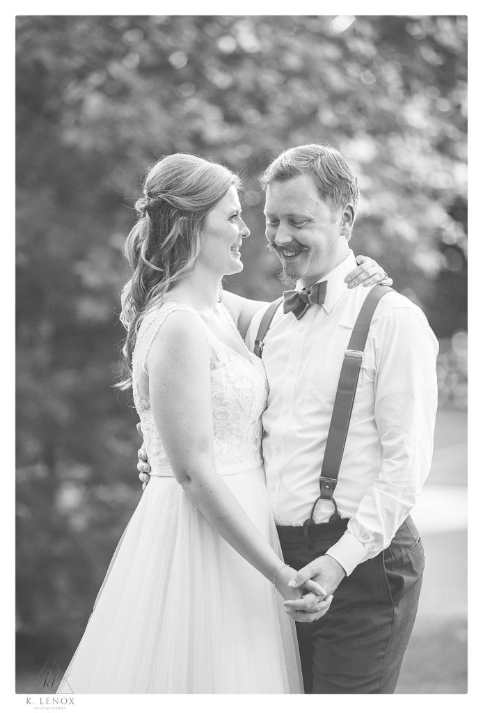 Bride and groom hold hands and laugh for a black and white photo.