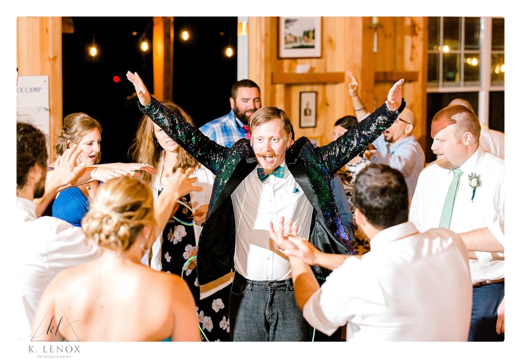 Groom wearing sparkly suit jacket dances at his wedding reception. 