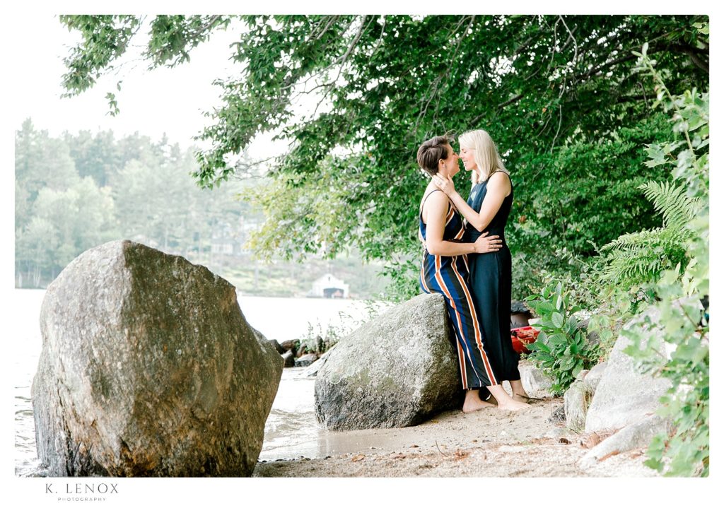 Engagement Photos at Lake Sunapee- two women near a rock at the shore of the lake. 
