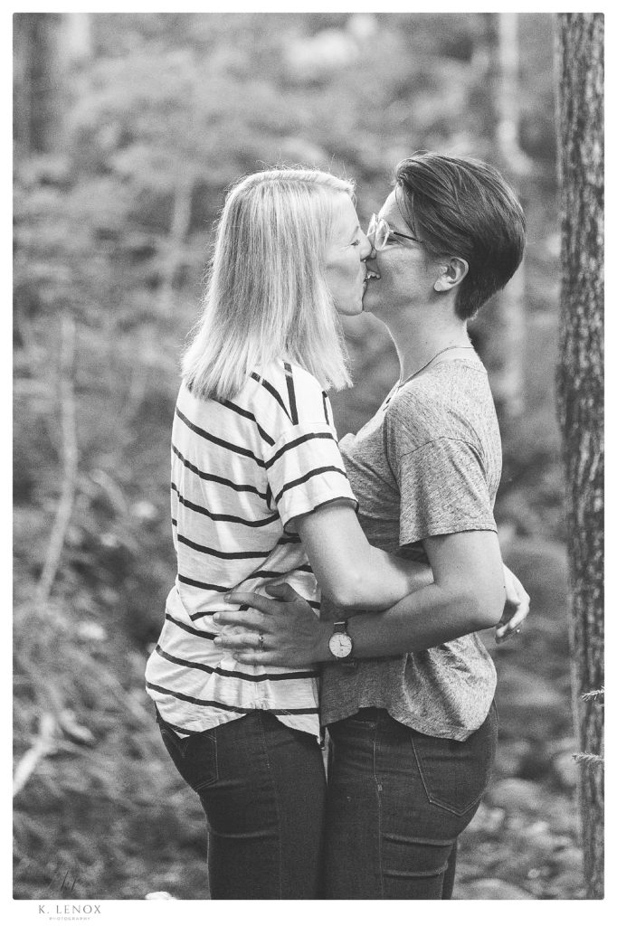 Black and White candid photo of a happy couple kissing in the woods during their engagement session