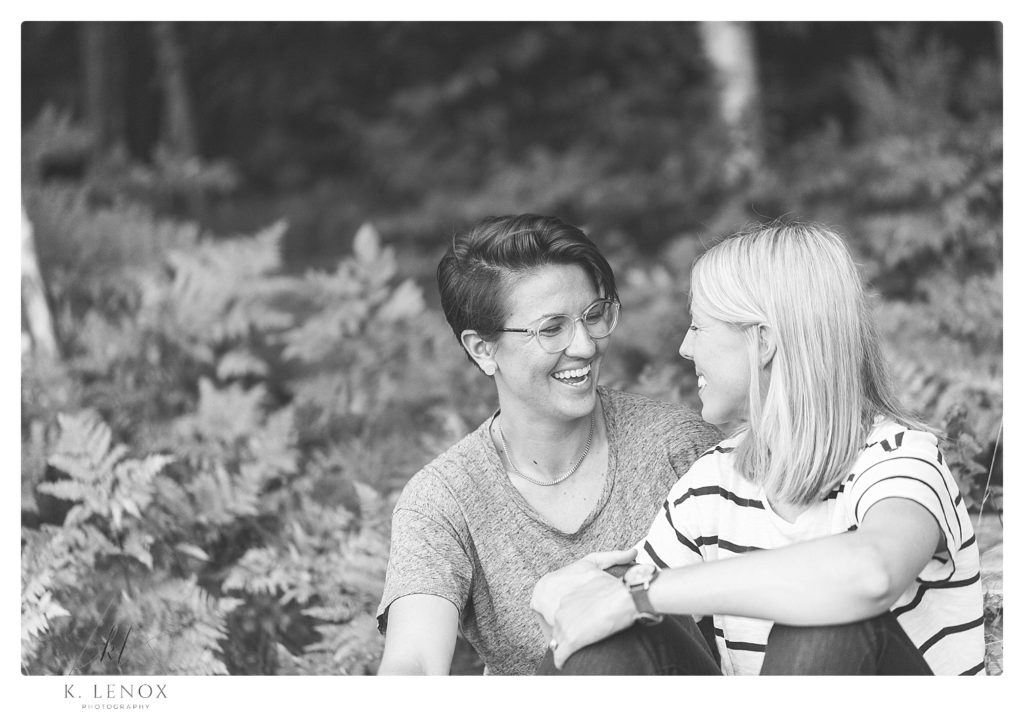 Candid black and white photo of two women laughing and talking. 