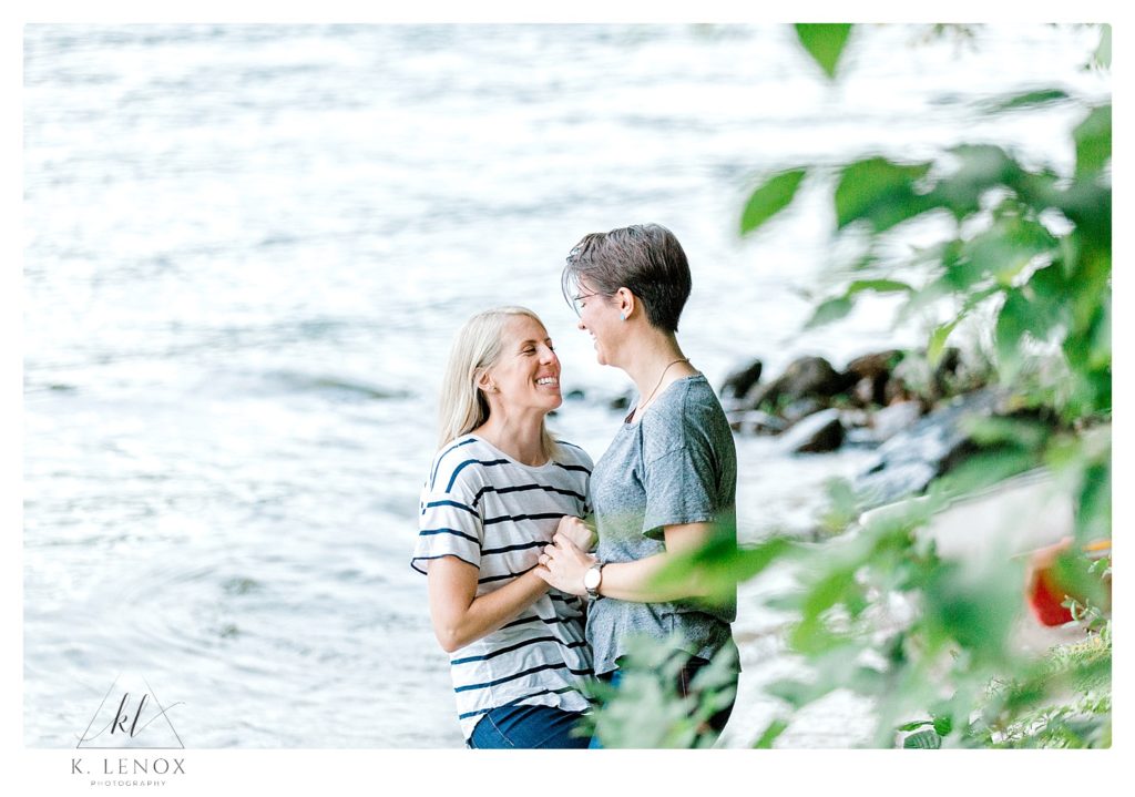 Candid photo of two women laughing and interacting during their engagement session at Lake Sunapee. 