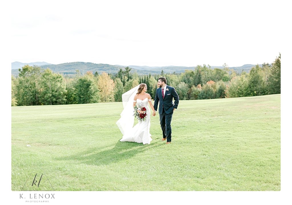 Bride and Groom walk together on the property in front of the Mountain View Grand in Whitefield NH. 