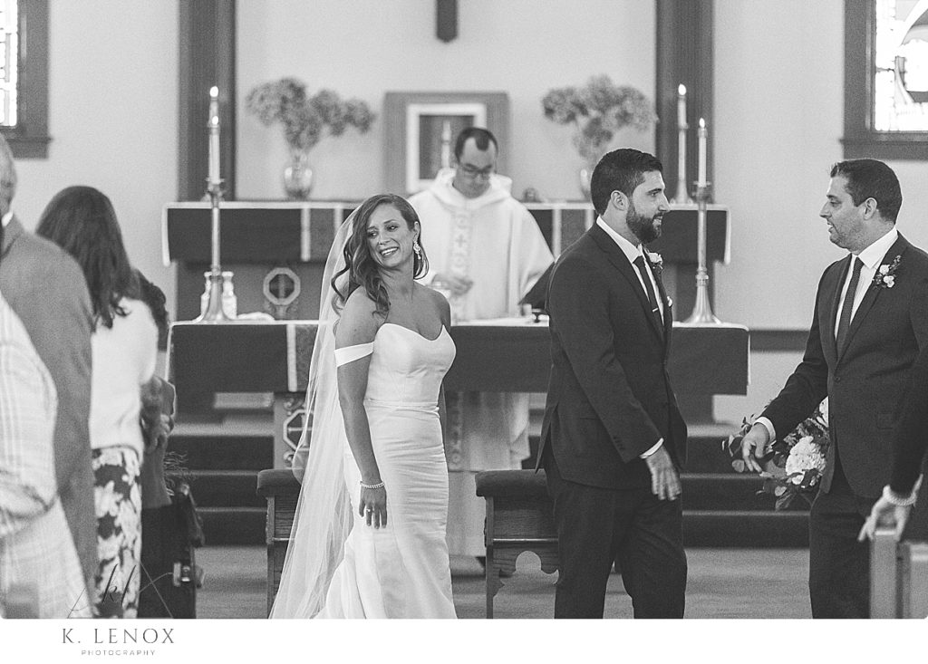 Black and White photo of a bride and groom offering "peace" during a catholic wedding ceremony/mass. 