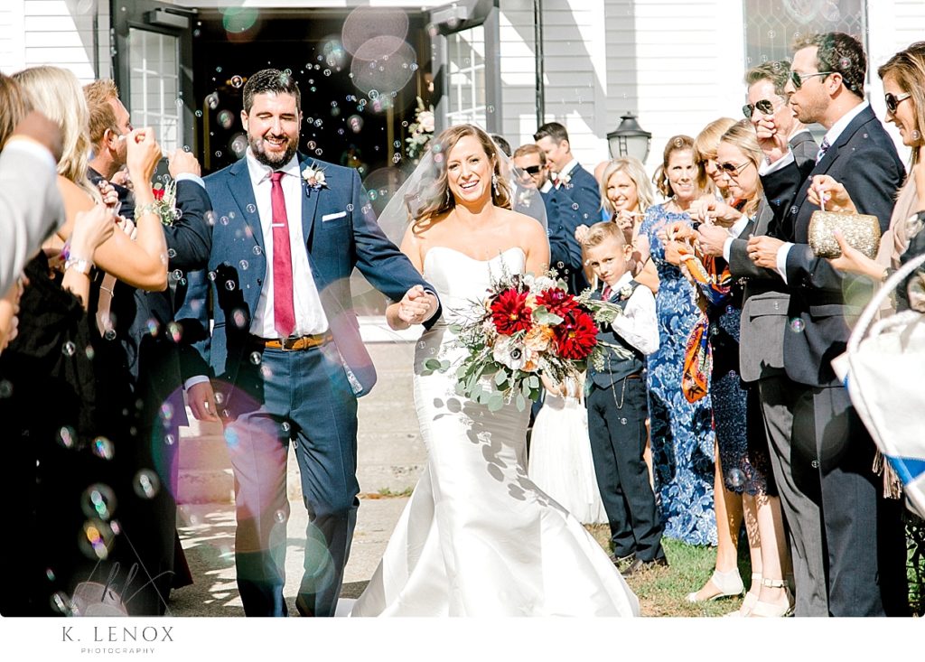 Bride and Groom walk out of the church to bubbles after their fall wedding ceremony. 