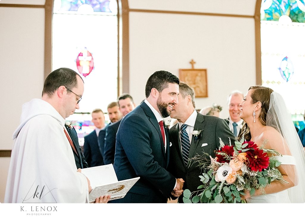 Father gives his daughter away and whispers something funny into the ear of the groom at St. Matthews Church in Whitefield NH> 