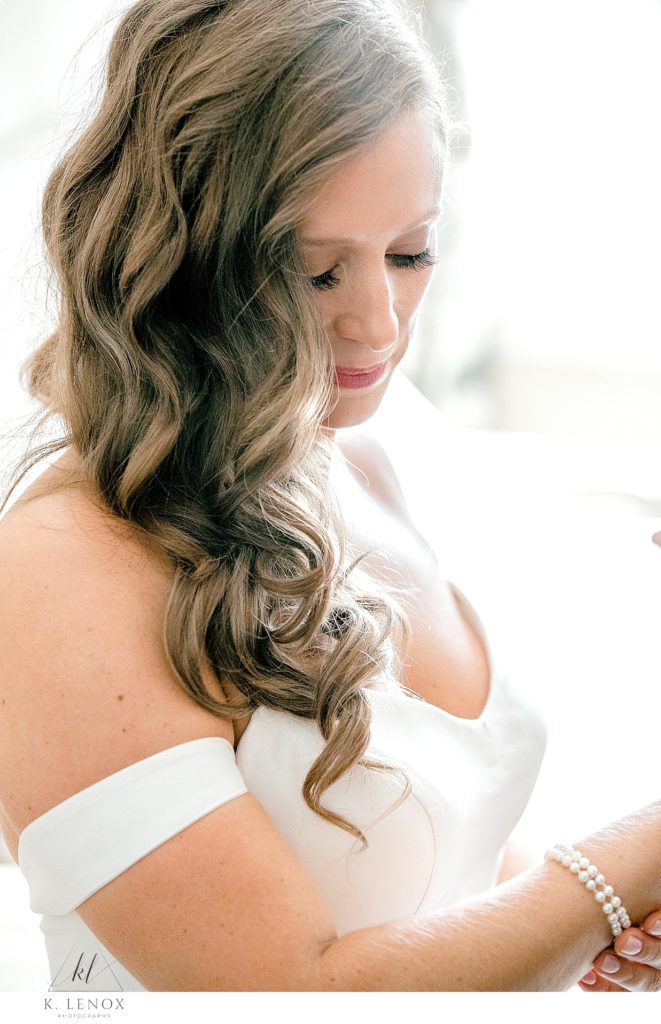 Bride puts on her pearl bracelet for her fall wedding. 