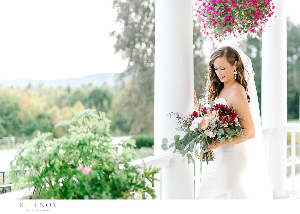 Beautiful Bride holds her fall bouquet and poses on the porch of the mountain view Grand. 