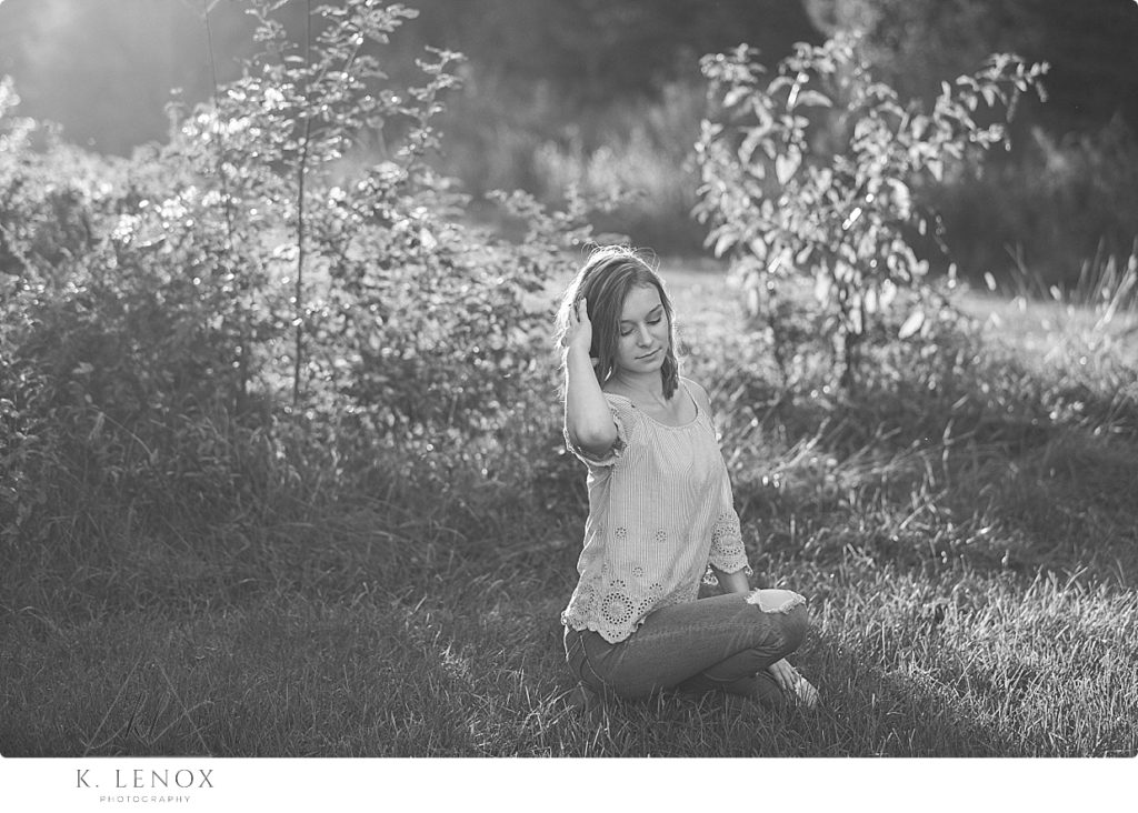 Black and White photo of a girl sitting in a field. 