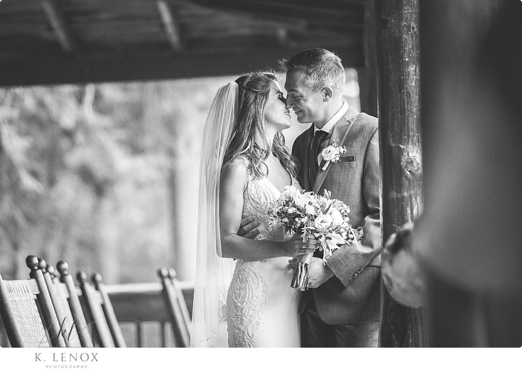 Black and White image of a Bride and Groom at a Camp Takodah Wedding, on the rustic porch overlooking the lake. 