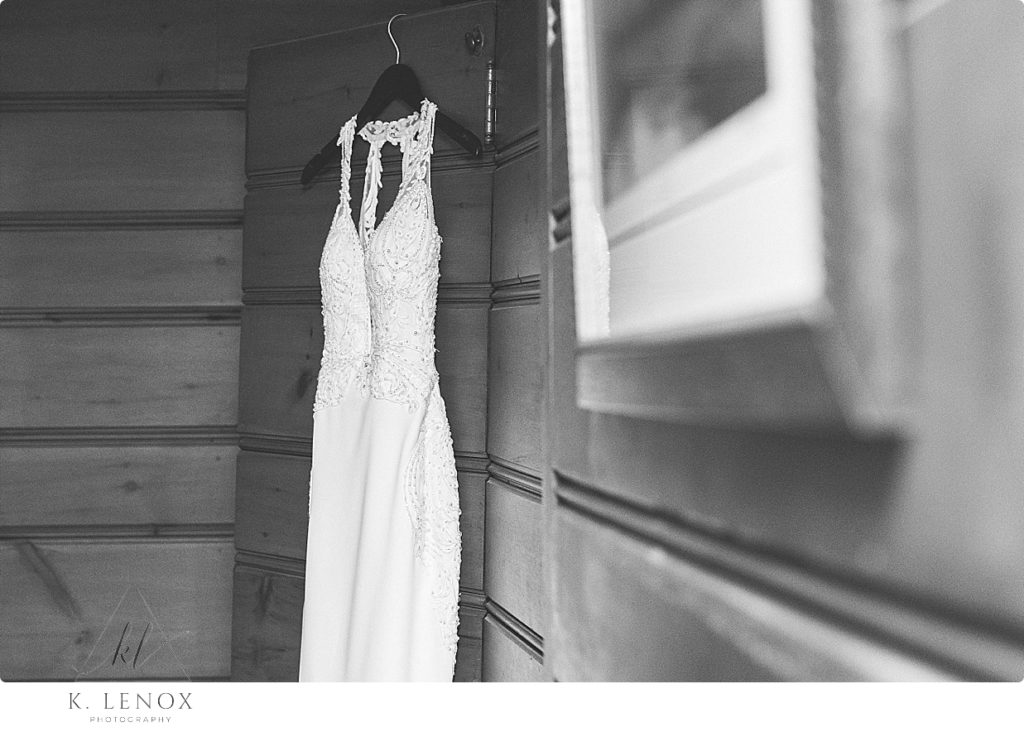 Black and White photo of a wedding dress hanging on the closet door in a lake house cabin in NH. 