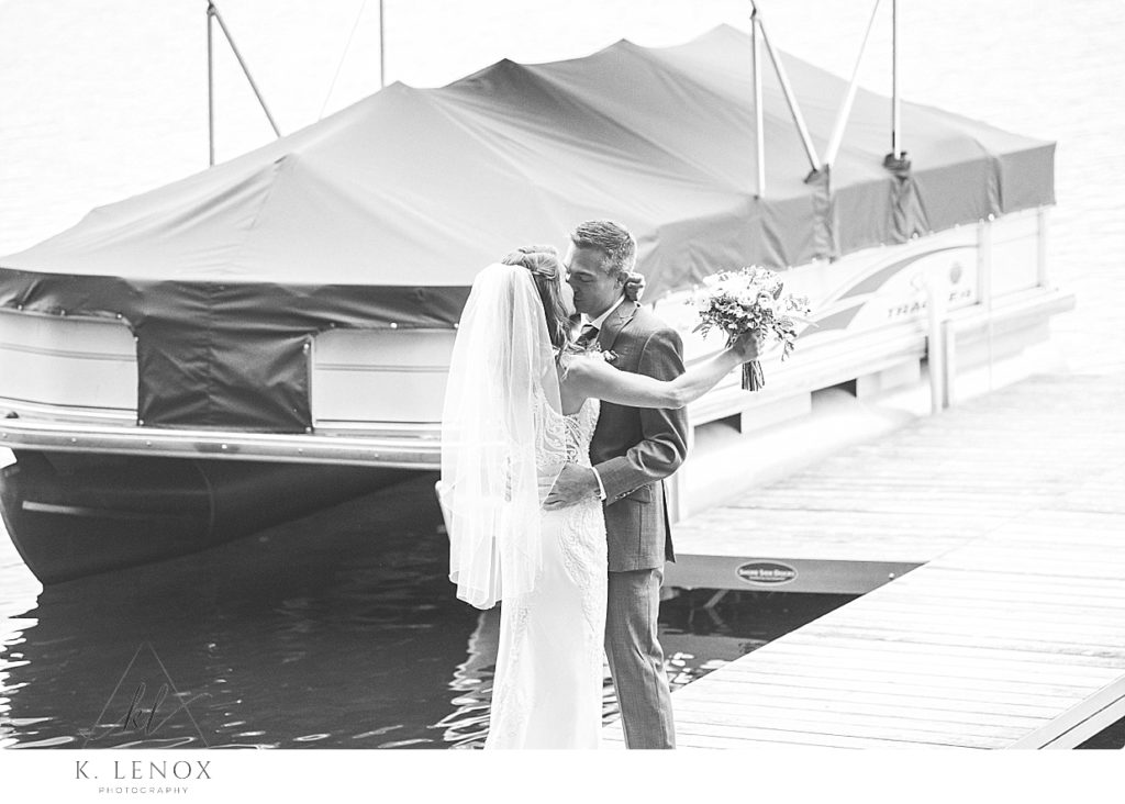 Black and White photo of a bride and groom having a kiss on their wedding day, while down on the dock at the lake. 