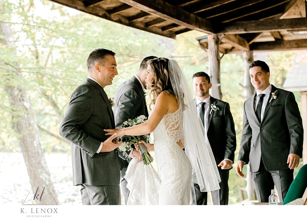 Candid Moment of a bride and groom talking on the porch of their rustic lakeside home. 