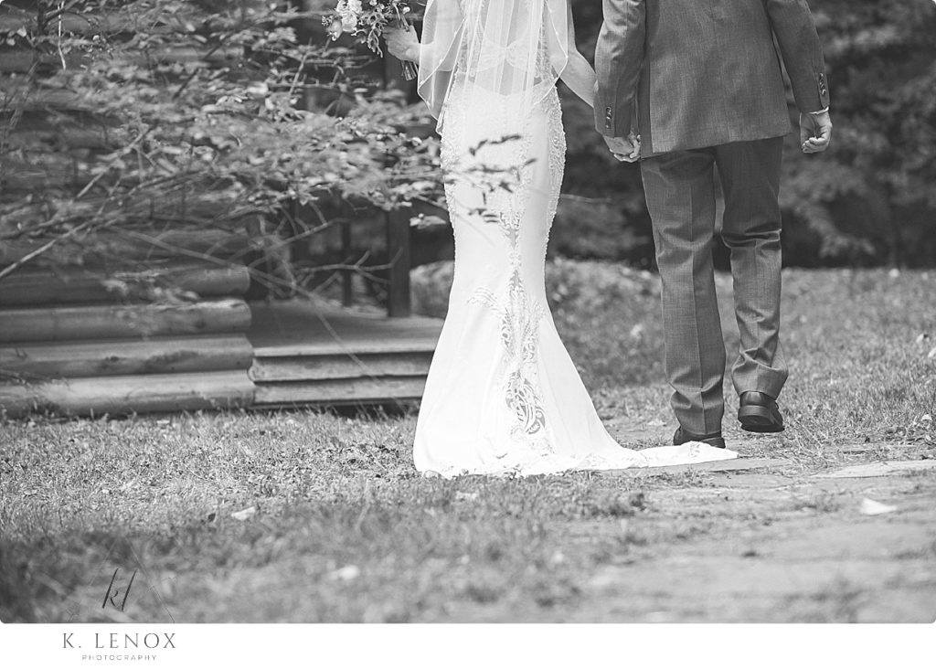 Black and White photo of a bride and groom walking away- showing her train. 