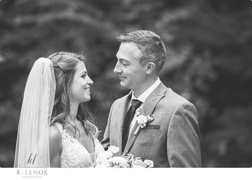 Black and white portrait of a bride and groom looking at each other lovingly. 