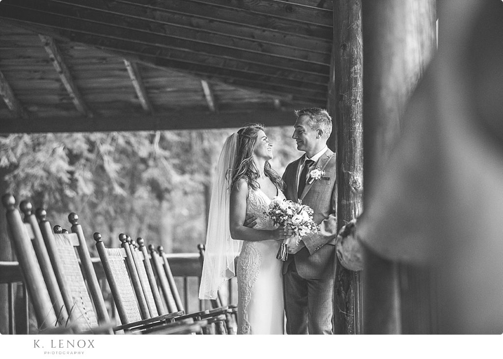 Black and White photo of a bride and groom on the rustic lodge porch at Camp Takodah after their wedding. 