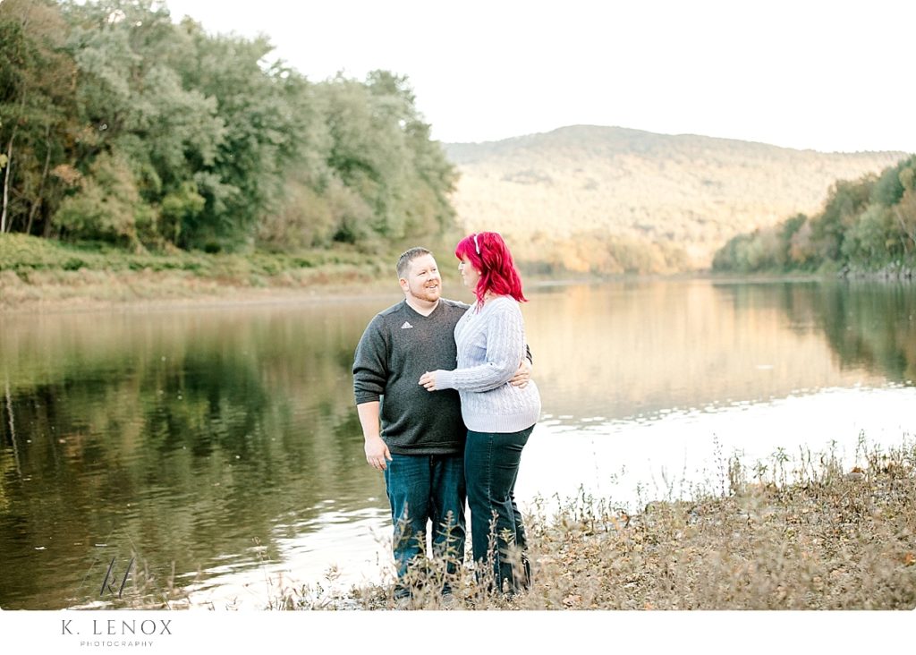 Candid photo of a man and woman standing near a river bank in VT. 