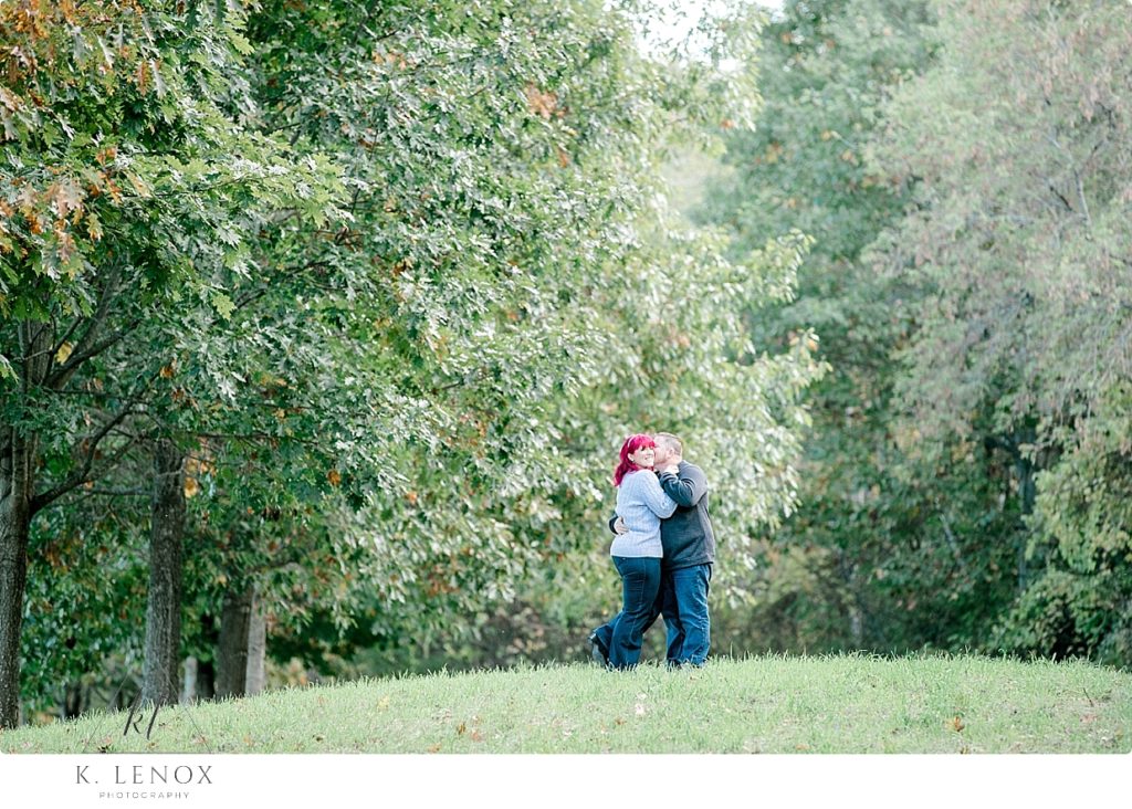 Woman and man hug and hold each other during their Engagement session at the Path of Life Garden in Vt. 