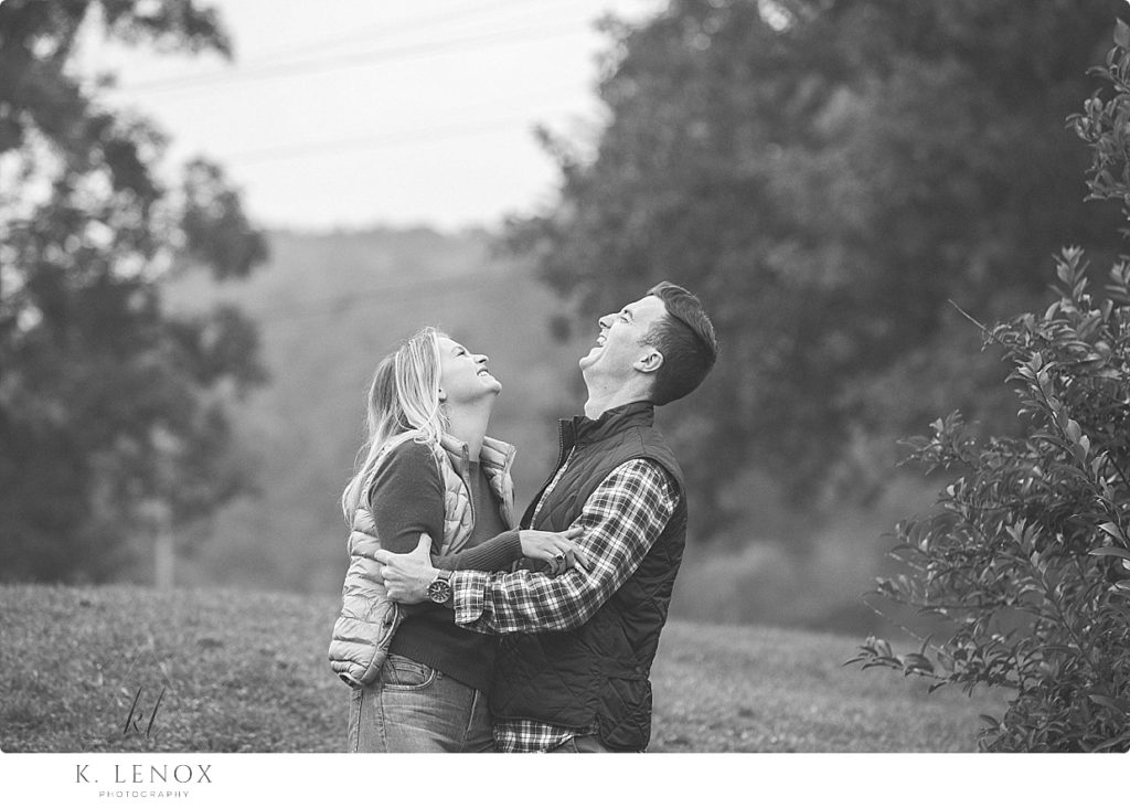 Black and White Candid photo of a man and woman laughing during their Fall Engagement Session at Scott Farm. 
