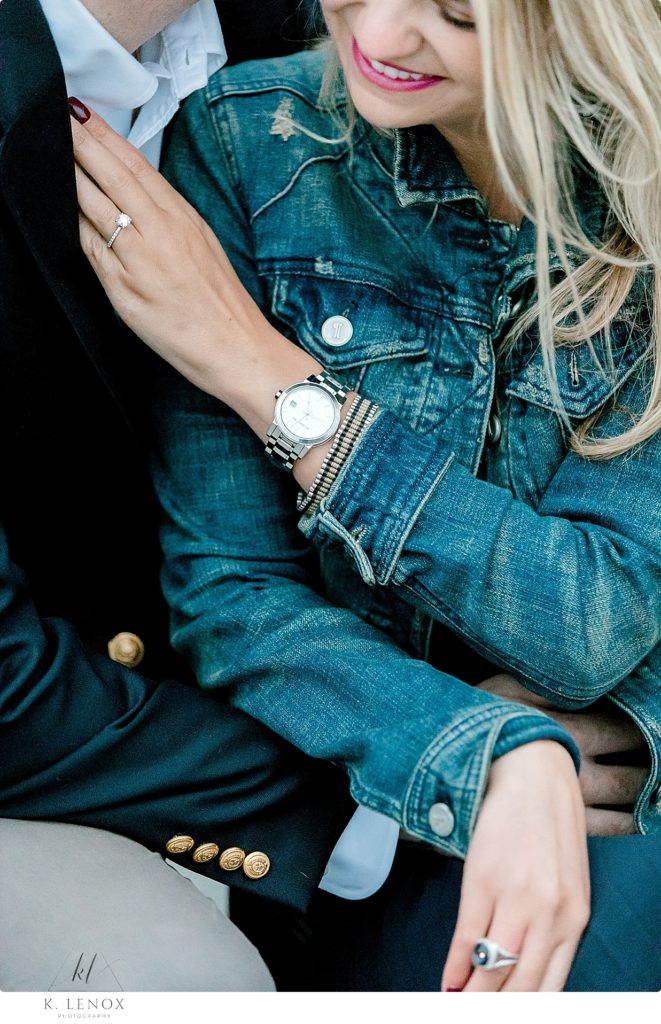 Detail photo of a womans engagement ring and her jean jacket. 