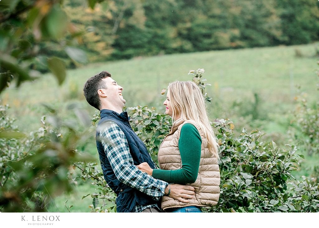 Candid Photo taken of a man and woman laughing during their engagement photo session at Scott Farm. 