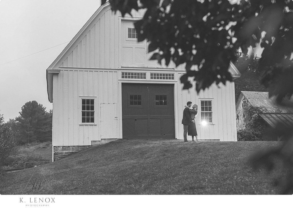 Couple hug in front of the Scott Farm Barn in Vermont. 