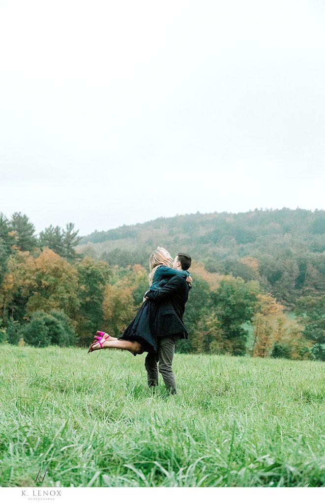 Man Spins his fiance around in a field during their fall engagement session in Vermont. 