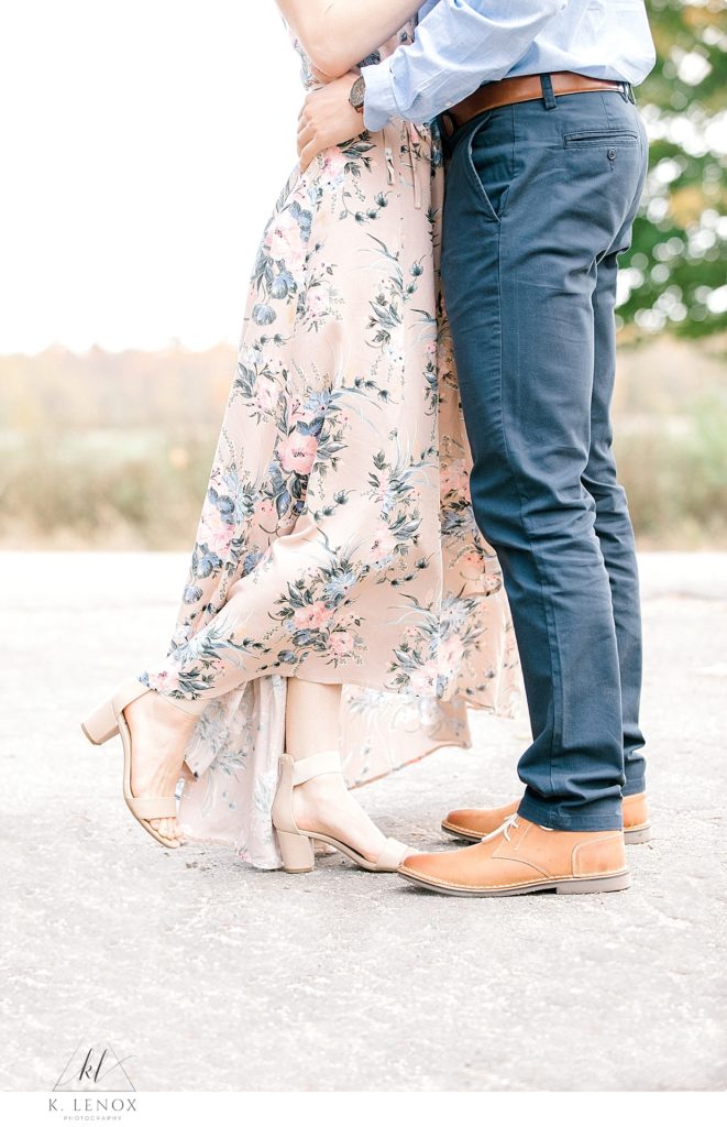 detail photo of a pink flowy floral skirt and a man in blue pants and leather shoes. 