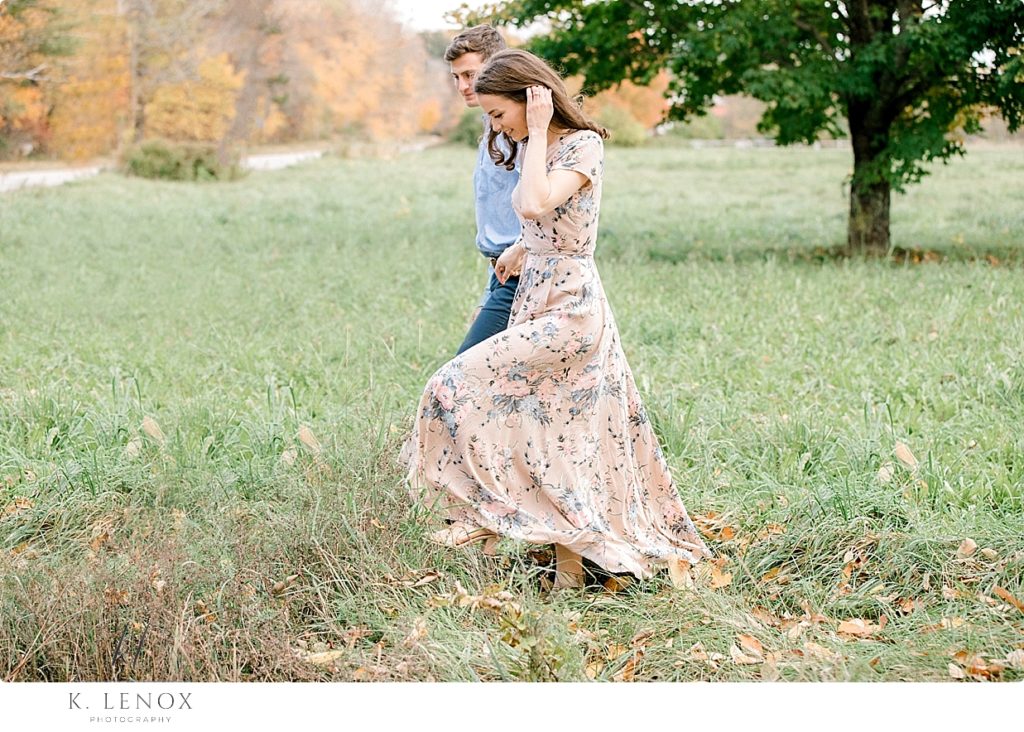 Light and Airy Engagement Photo showing a candid moment of a man and woman walking in a field. 